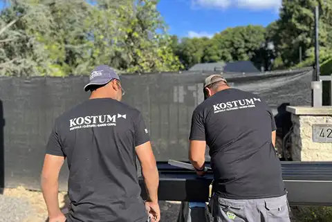 Deux installateurs qui montent un portail Kostum